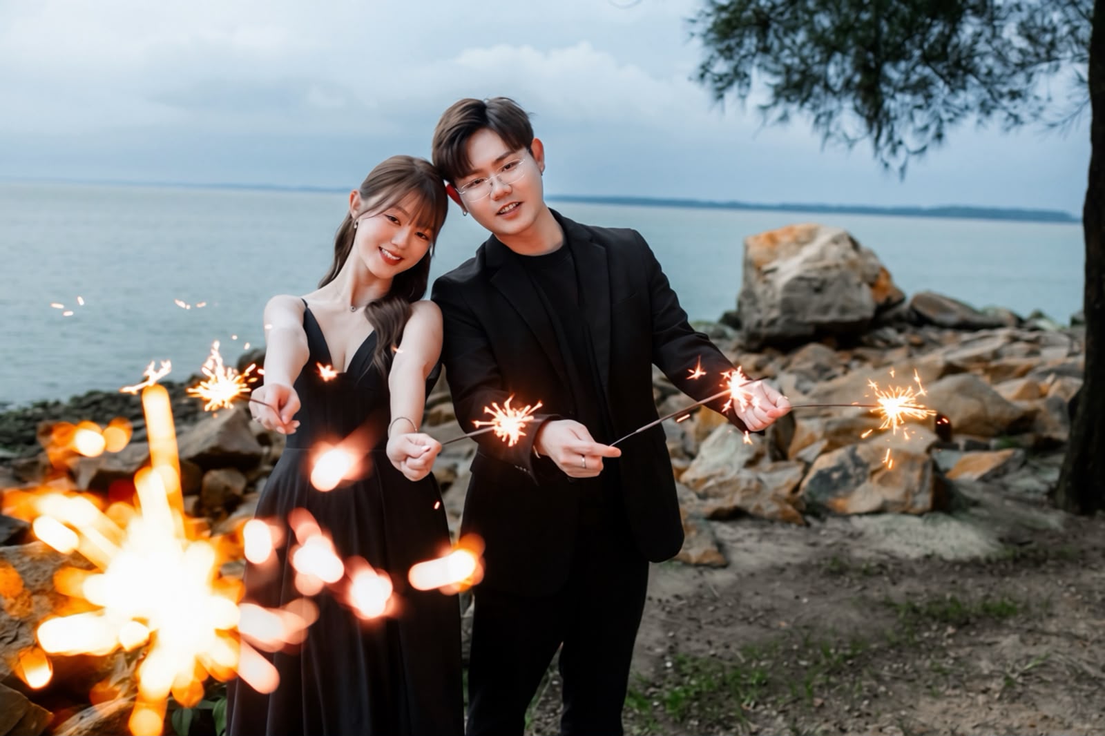 Clifford and Shuzhen celebrating with sparklers by the sea